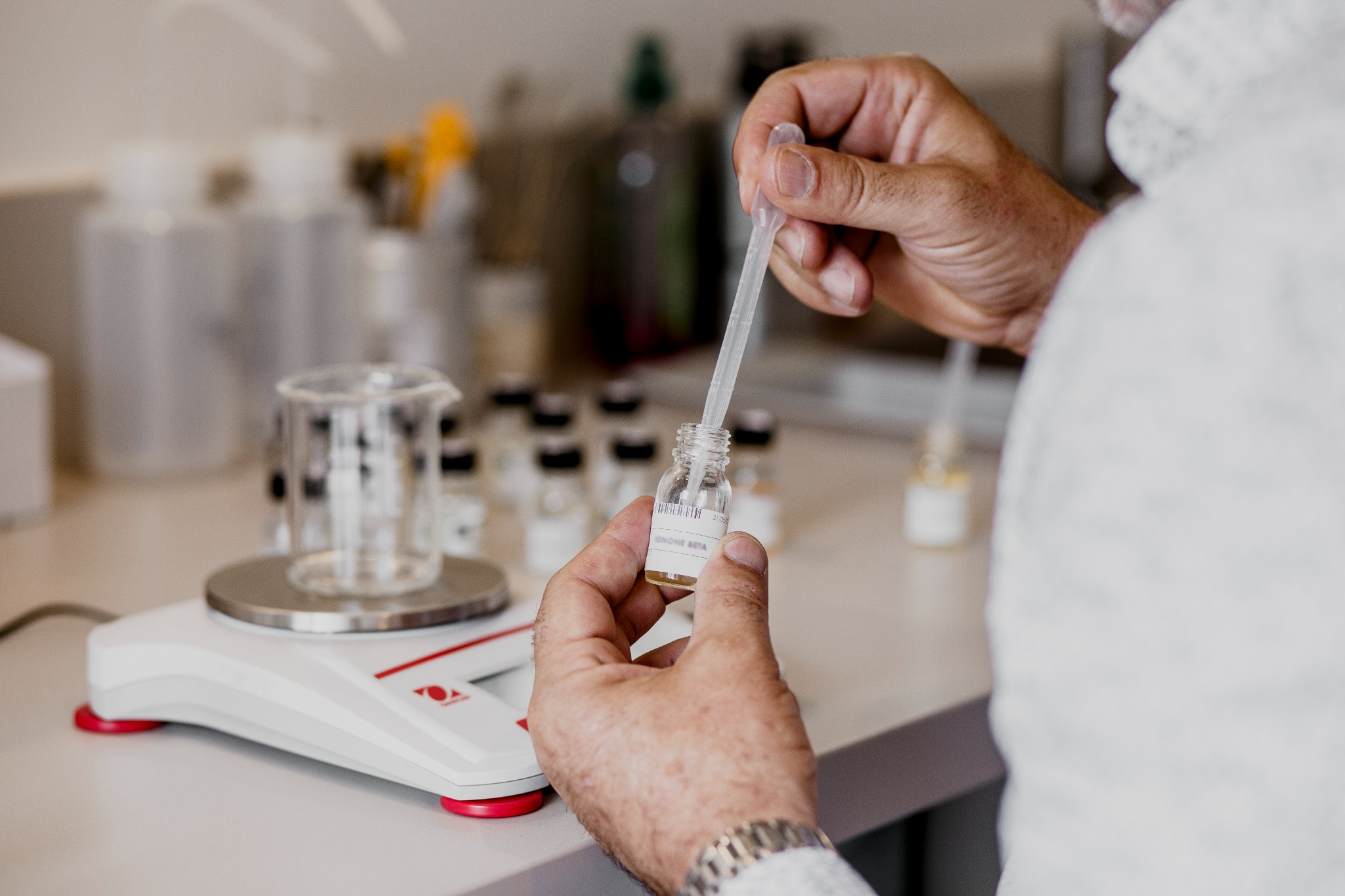 Geste de formulation d’un parfum GEODORA avec pipette et matières premières